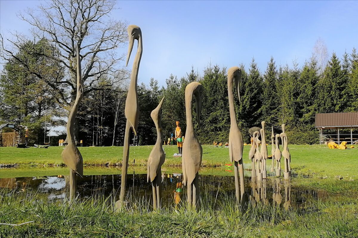 dzērvju koka skulptūras kuras ir ievietotas dīķī